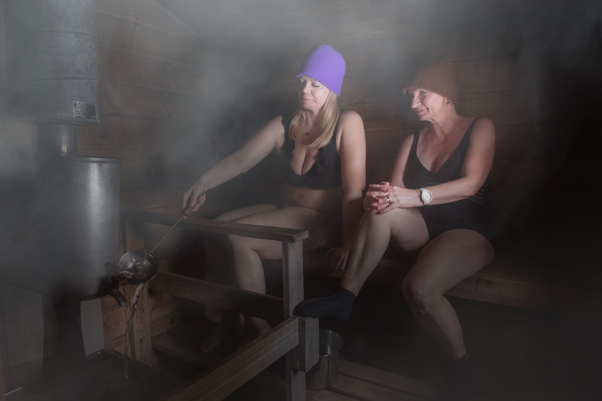 Women wearing sauna hats and throwing löyly.