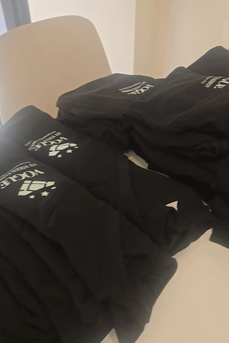 Rolled black t-shirts with a white logo and text placed on a surface.