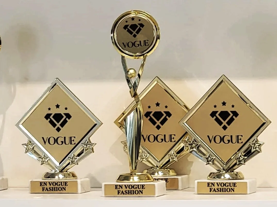 Four trophies with the Vogue logo and the phrase "En Vogue Fashion" on the bases. The trophies have a diamond shape with stars at the corners.