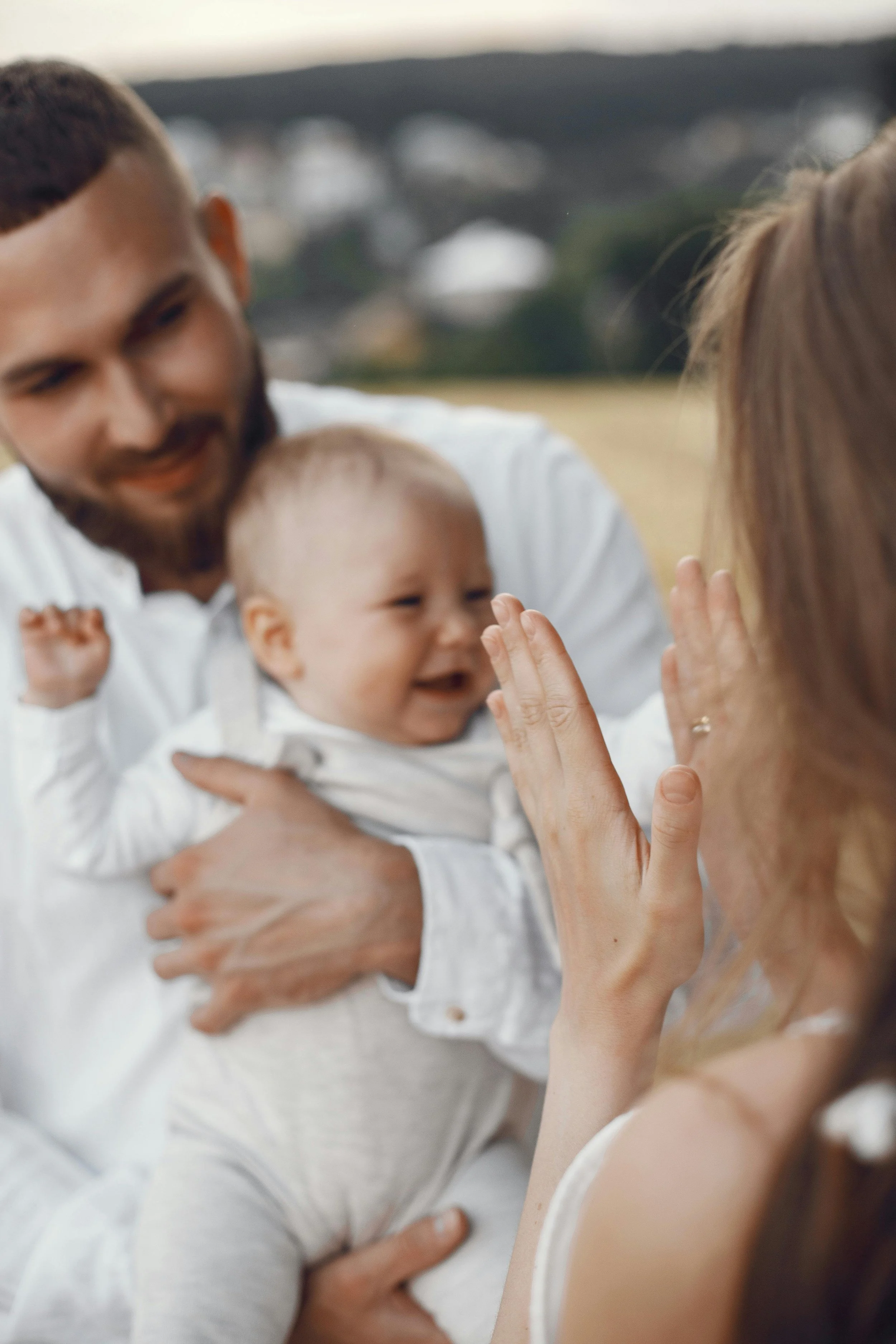 Une femme, un homme et un bébé souriant, partageant un moment de tendresse et d'affection en extérieur.