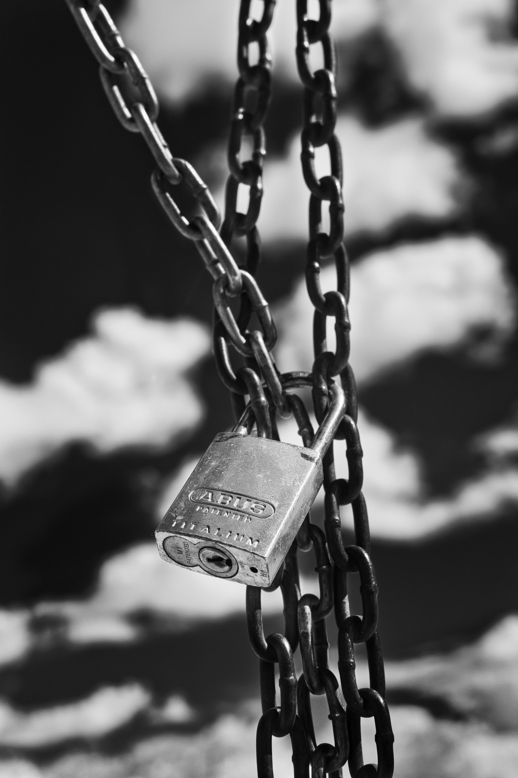 Close-up of a padlock attached to chains, with a blurred background.