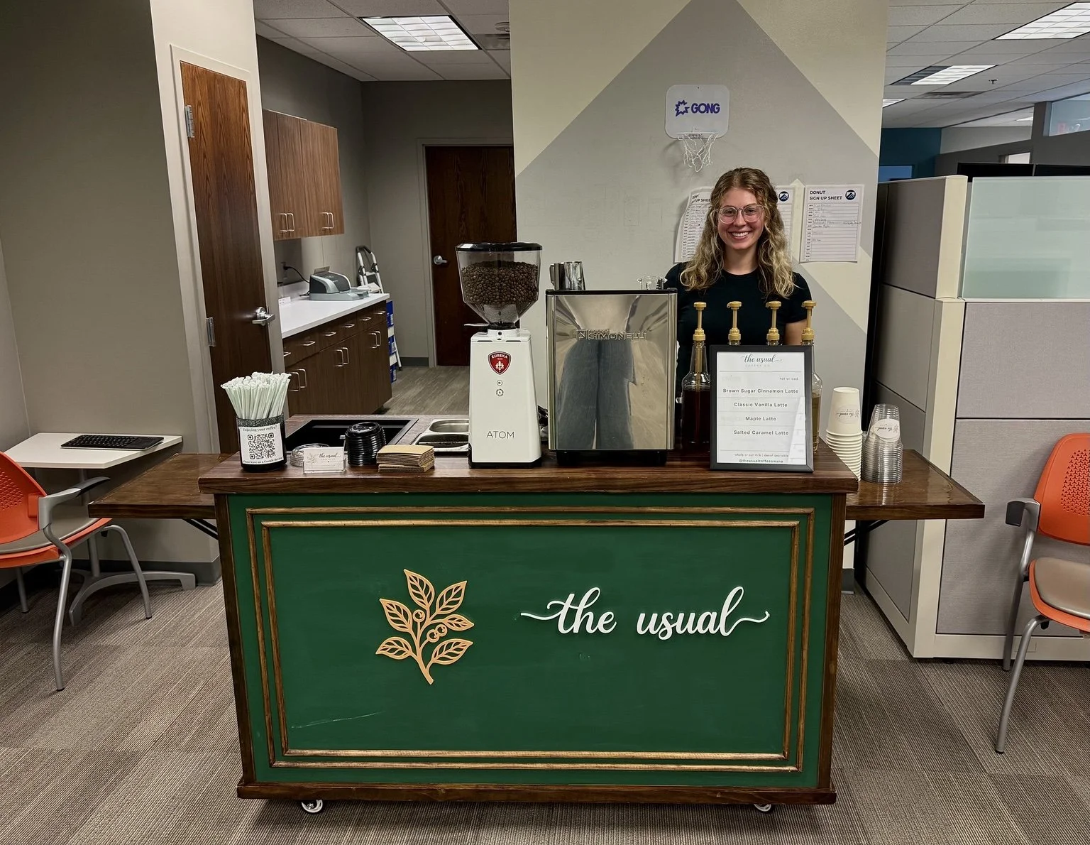 A barista at The Usual Coffee Co. green coffee cart set up in an office.