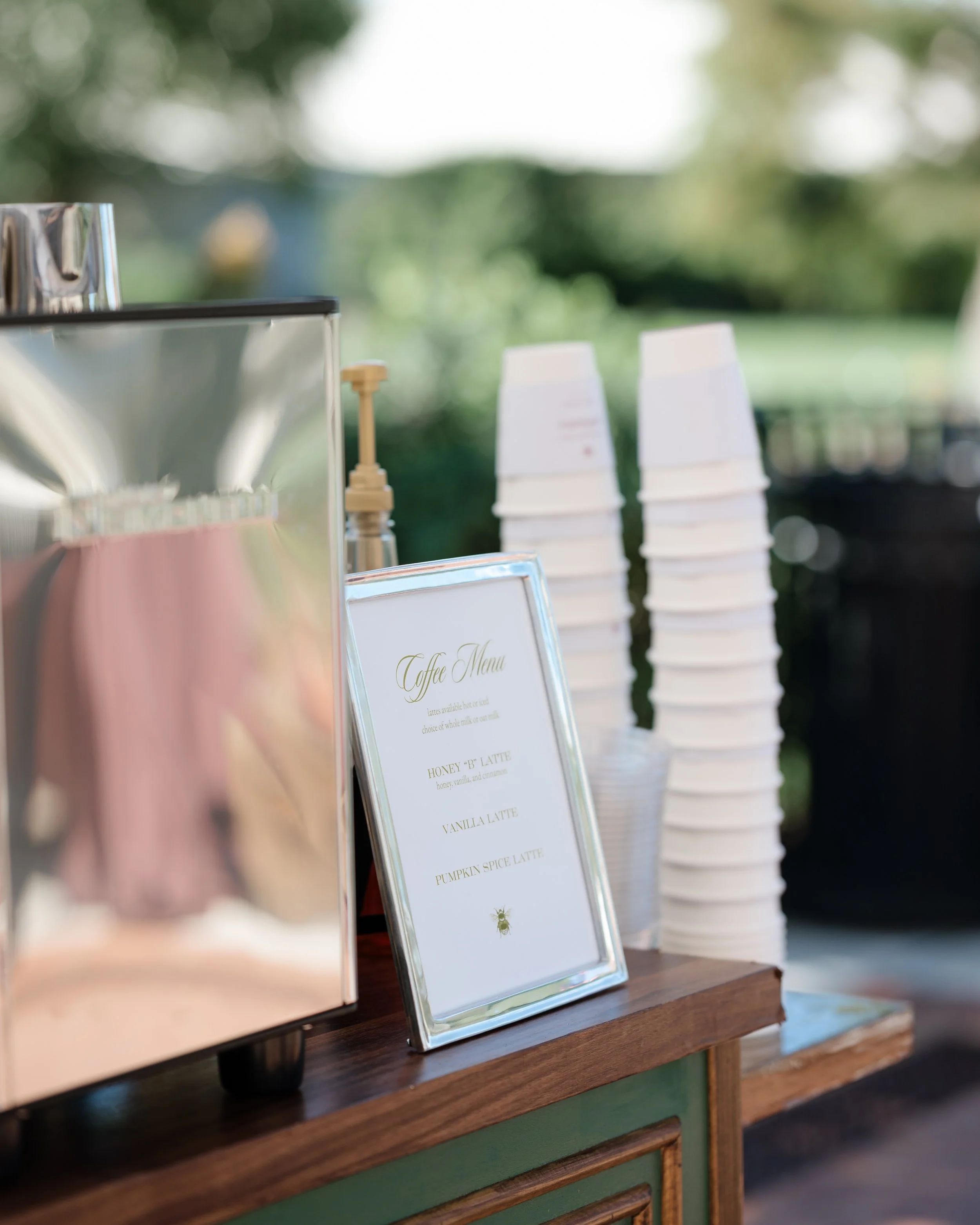 Personalized wedding coffee menu beside stacked cups on the espresso cart.