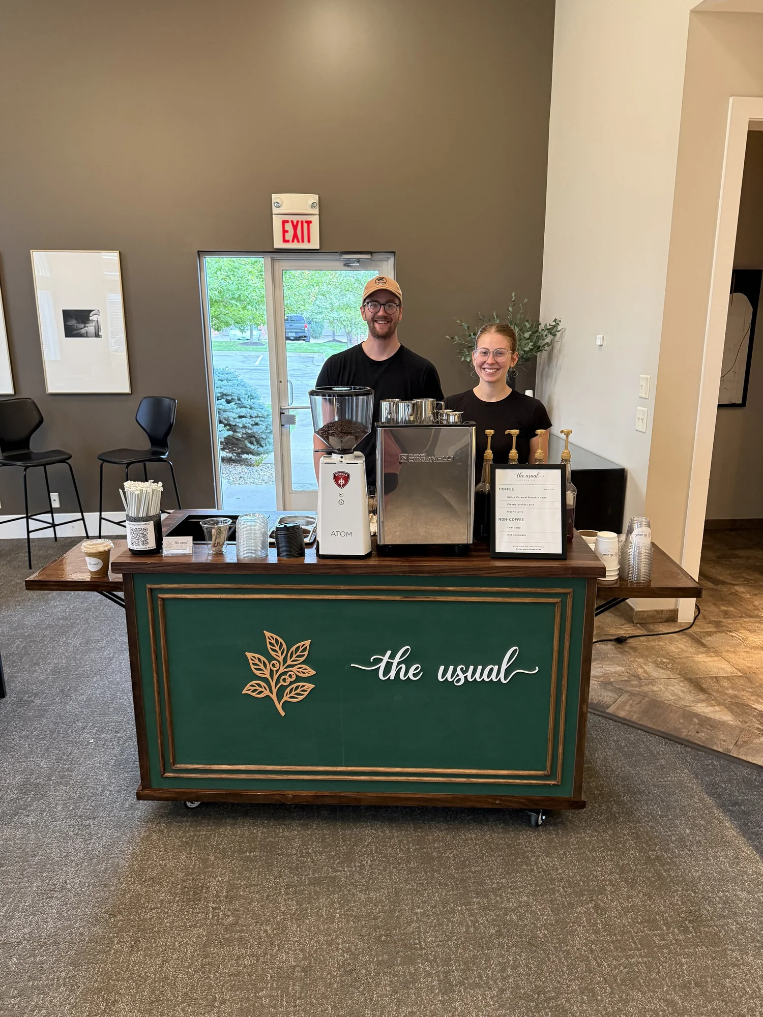 Two The Usual Coffee Co. baristas welcoming guests from our green and gold espresso cart at Broadmoor Hills.