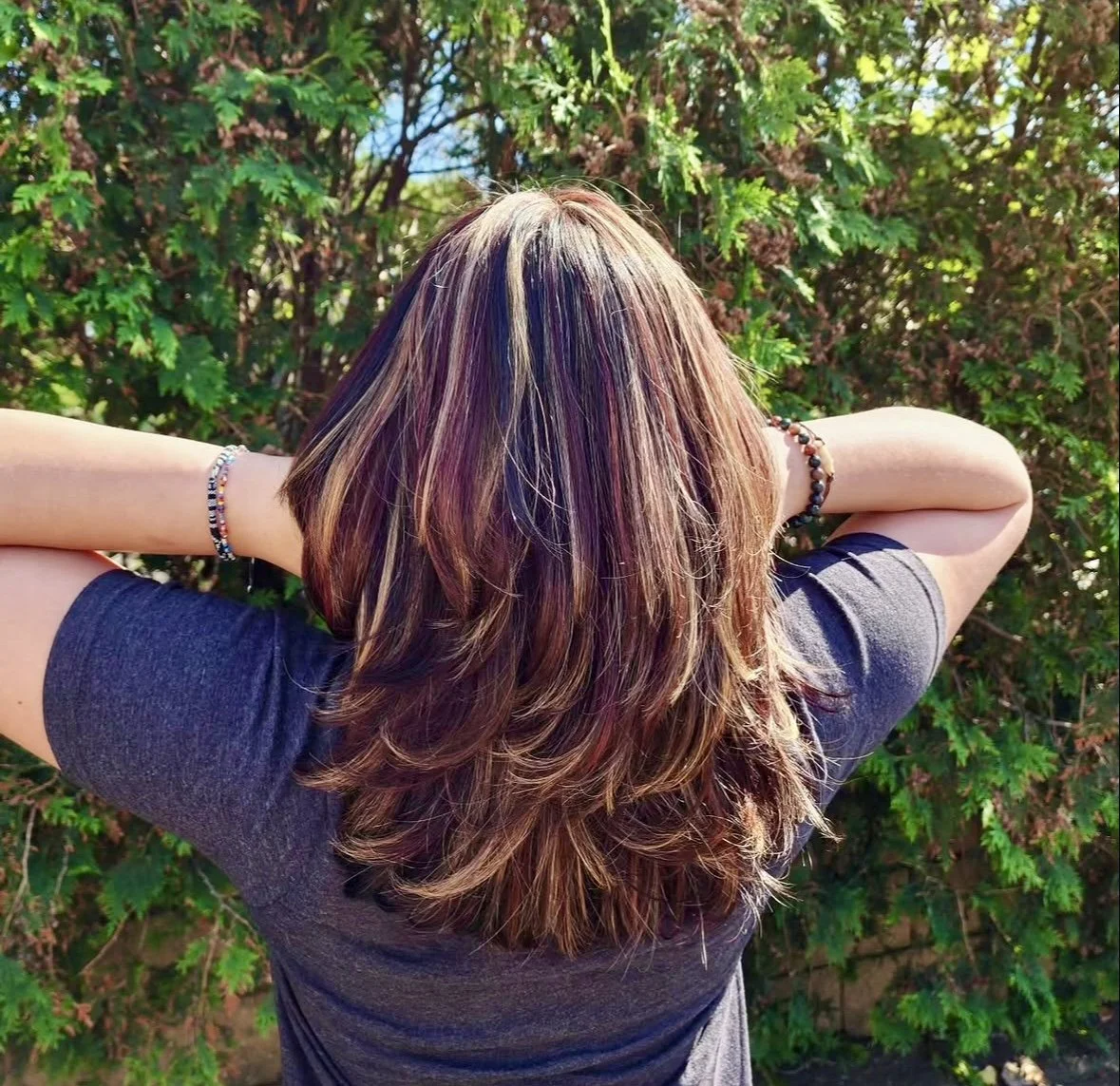 Stylist arranging a woman’s layered brunette hair.
