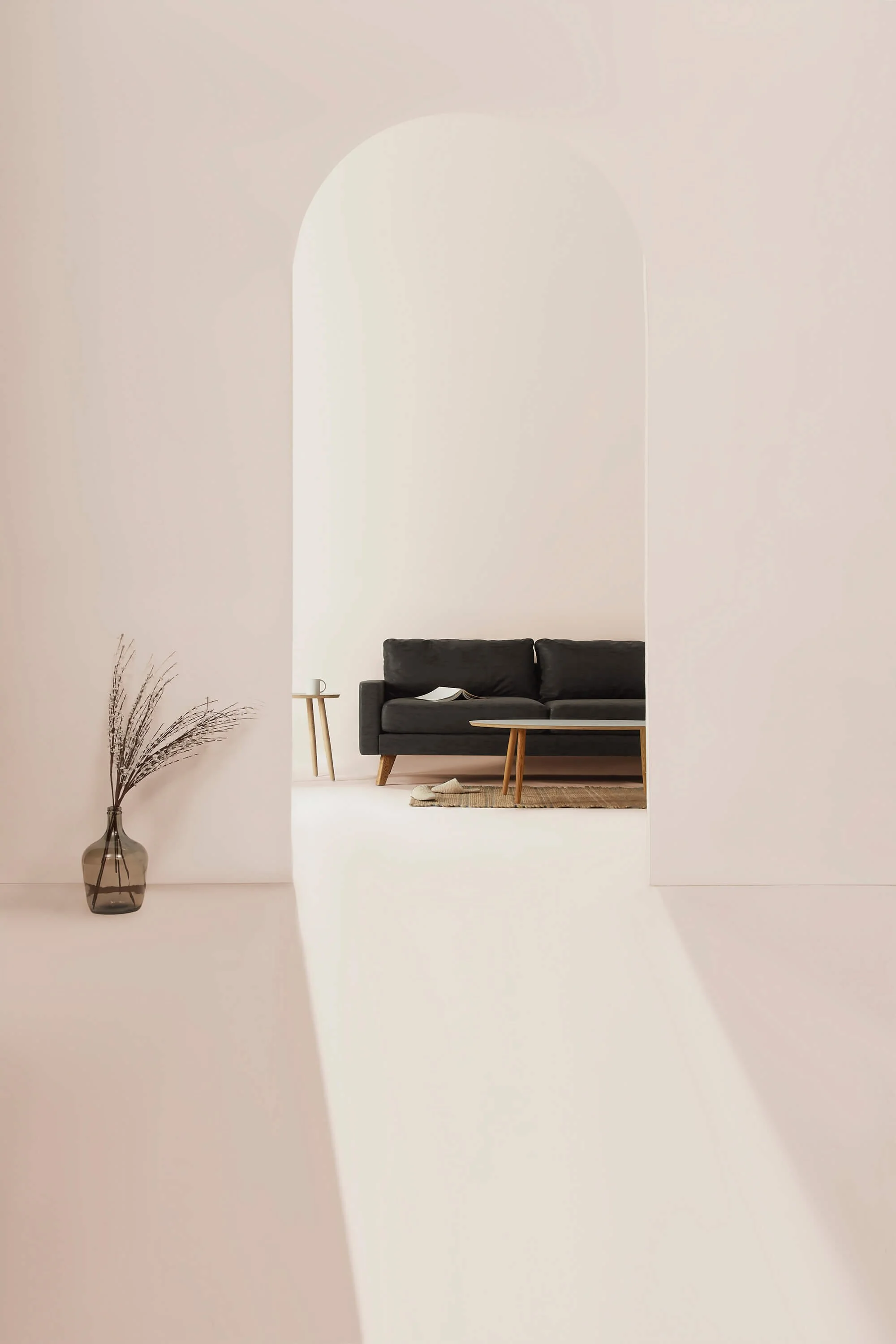 Minimalist living room with a black sofa, wooden coffee table, woven rug, and decorative vase of dried branches