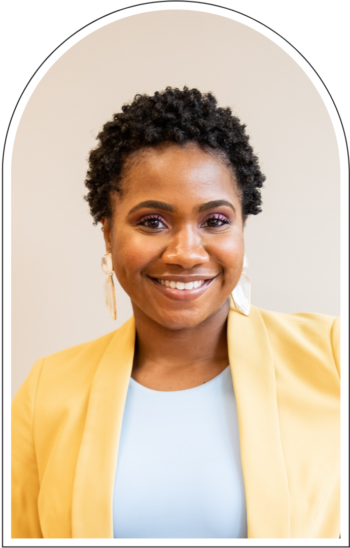 Smiling Black woman with short natural hair wearing a yellow blazer and statement earrings