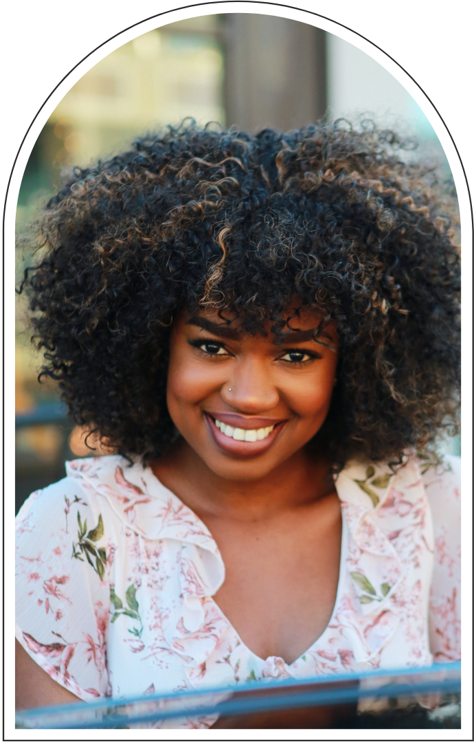 Smiling woman with voluminous curly hair wearing a floral blouse