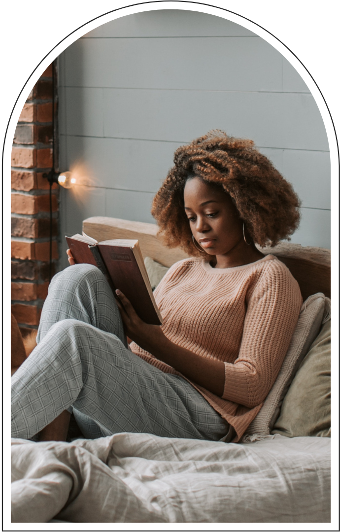 Woman reading a book while relaxing on a bed in a cozy bedroom