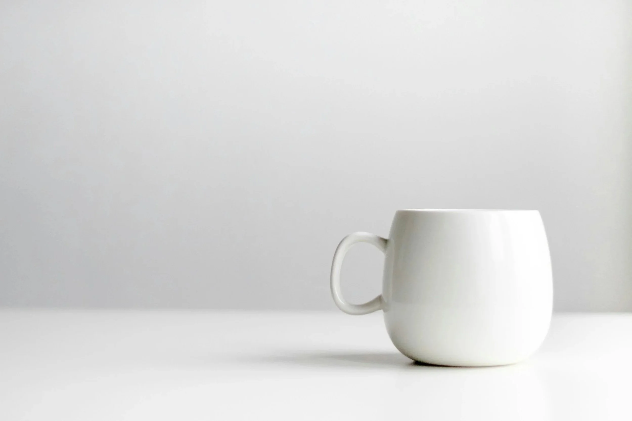 White ceramic mug on a white surface against a light gray background
