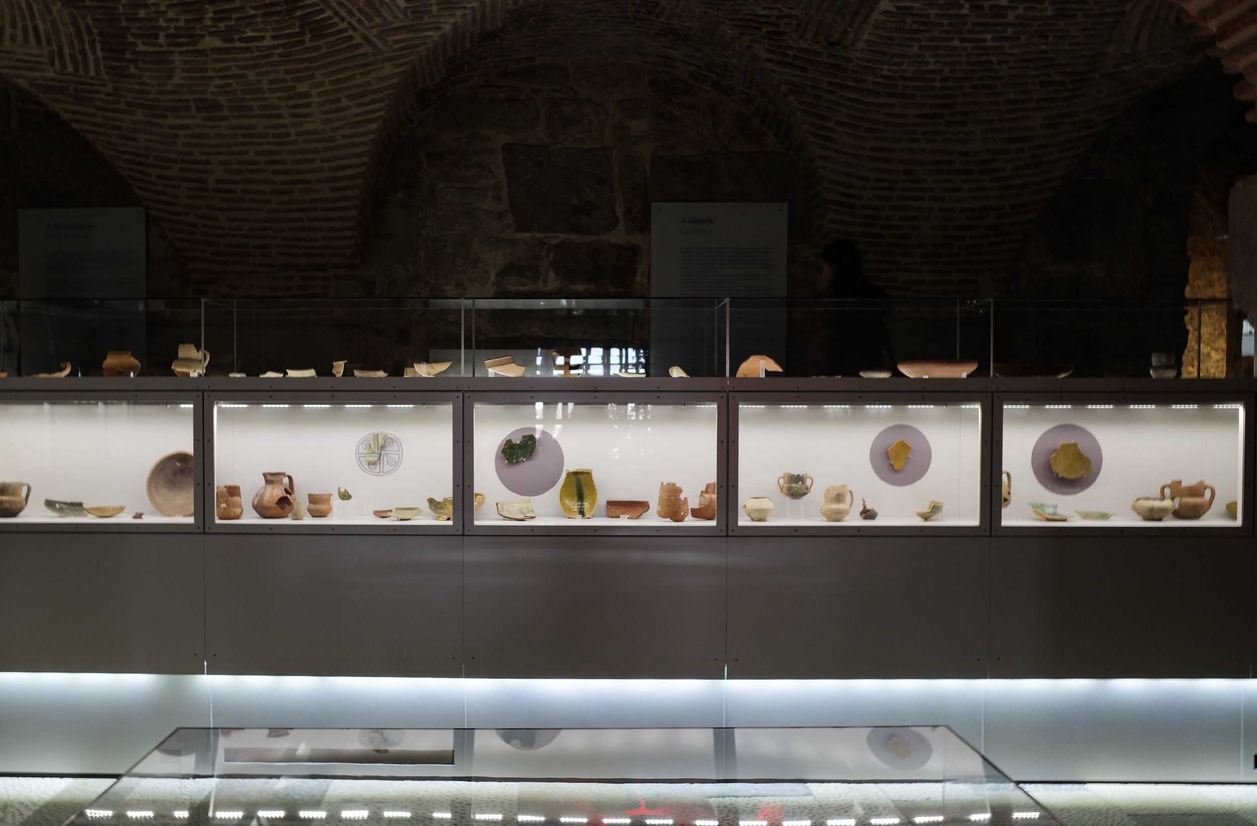 Display case containing various ancient pottery artifacts in a museum exhibit.