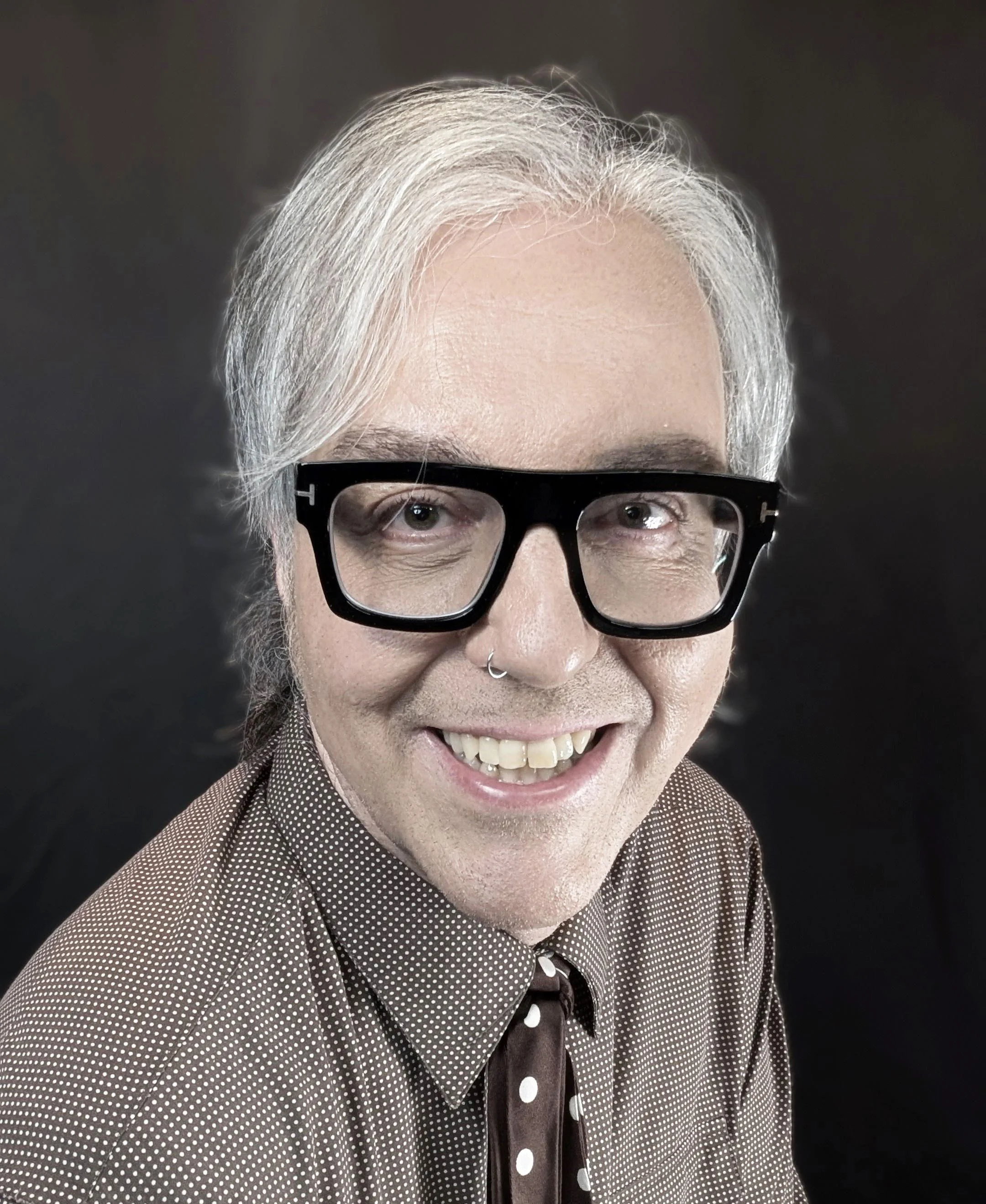 Close-up of Justin J. DuPré, smiling, against a dark background.