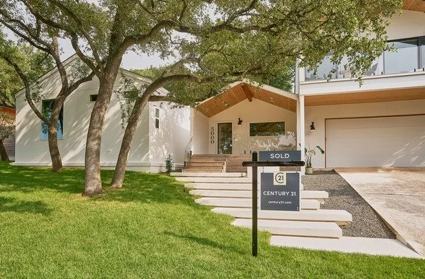 Modern two-story house with a large tree in frontyard, front steps leading to entrance, and a "Sold" sign from Century 21 real estate.