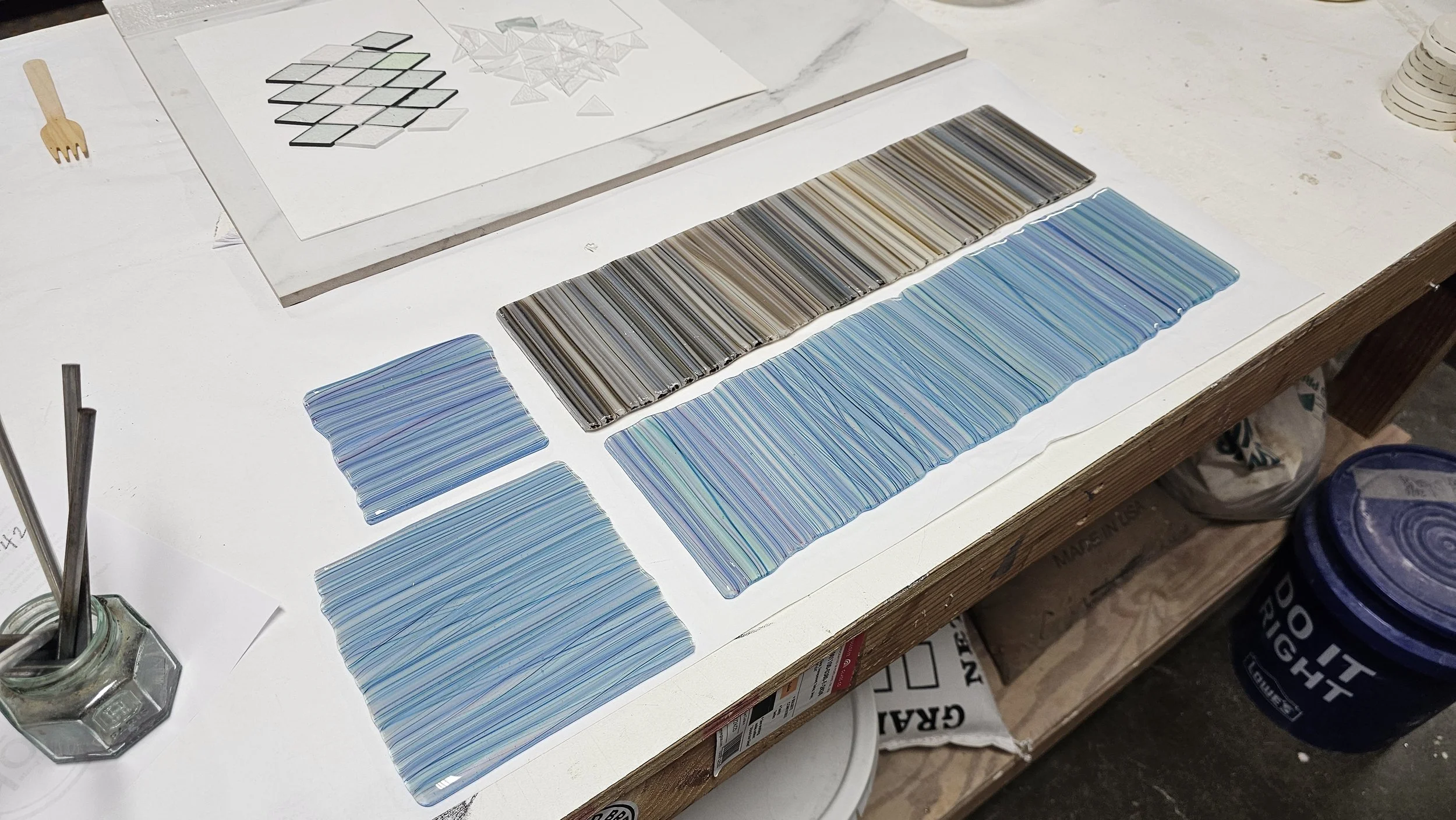 Colorful glass or plastic samples with various patterns and colors, laid out on a white surface for comparison or selection.