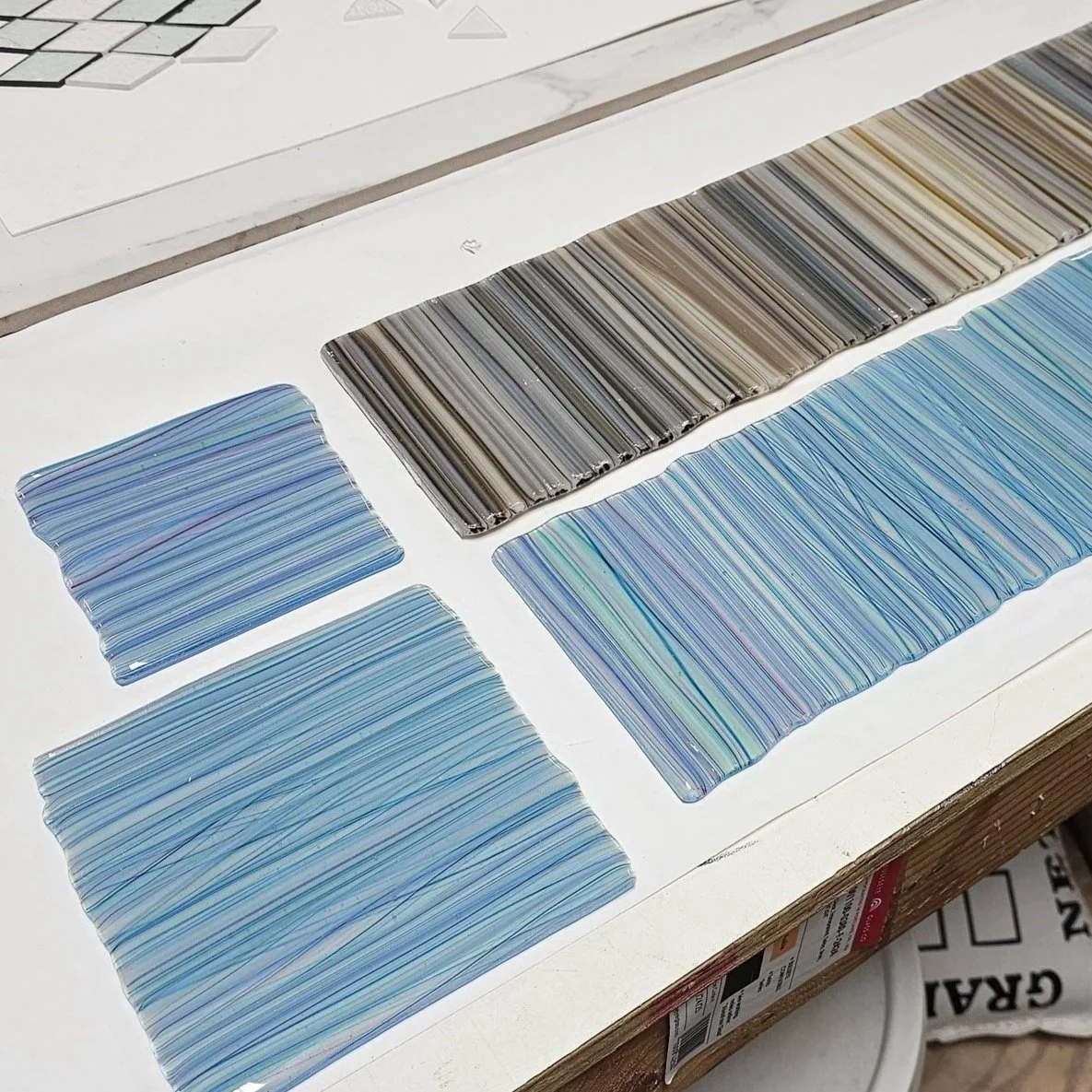 Color swatches with various striped patterns in shades of blue, brown, and multicolored, laid out on a white surface.