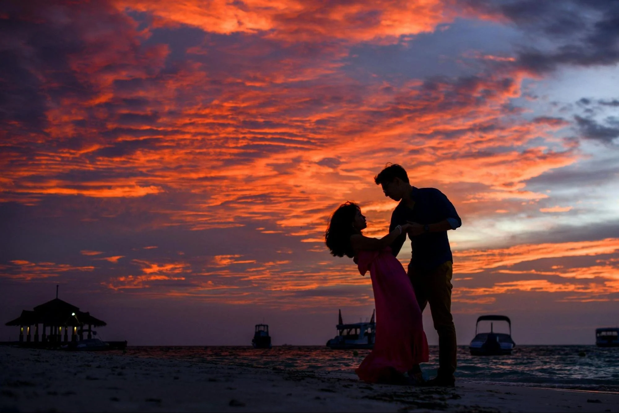 Couple embracing on a beach under a vivid sunset