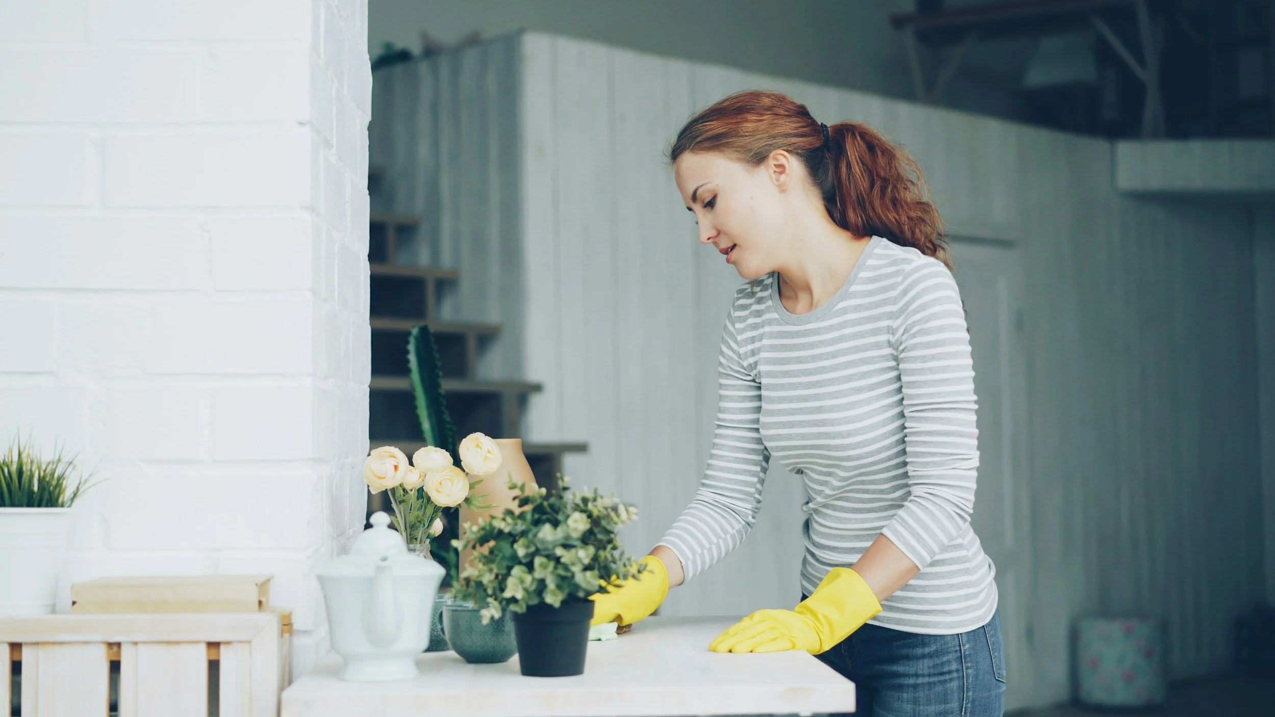 a woman with yellow cleaning gloves wiping down a table