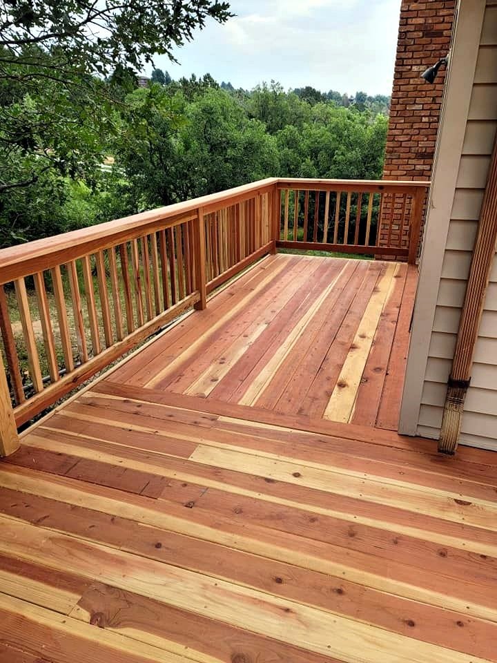 Wooden balcony with a railing overlooking a green forest.