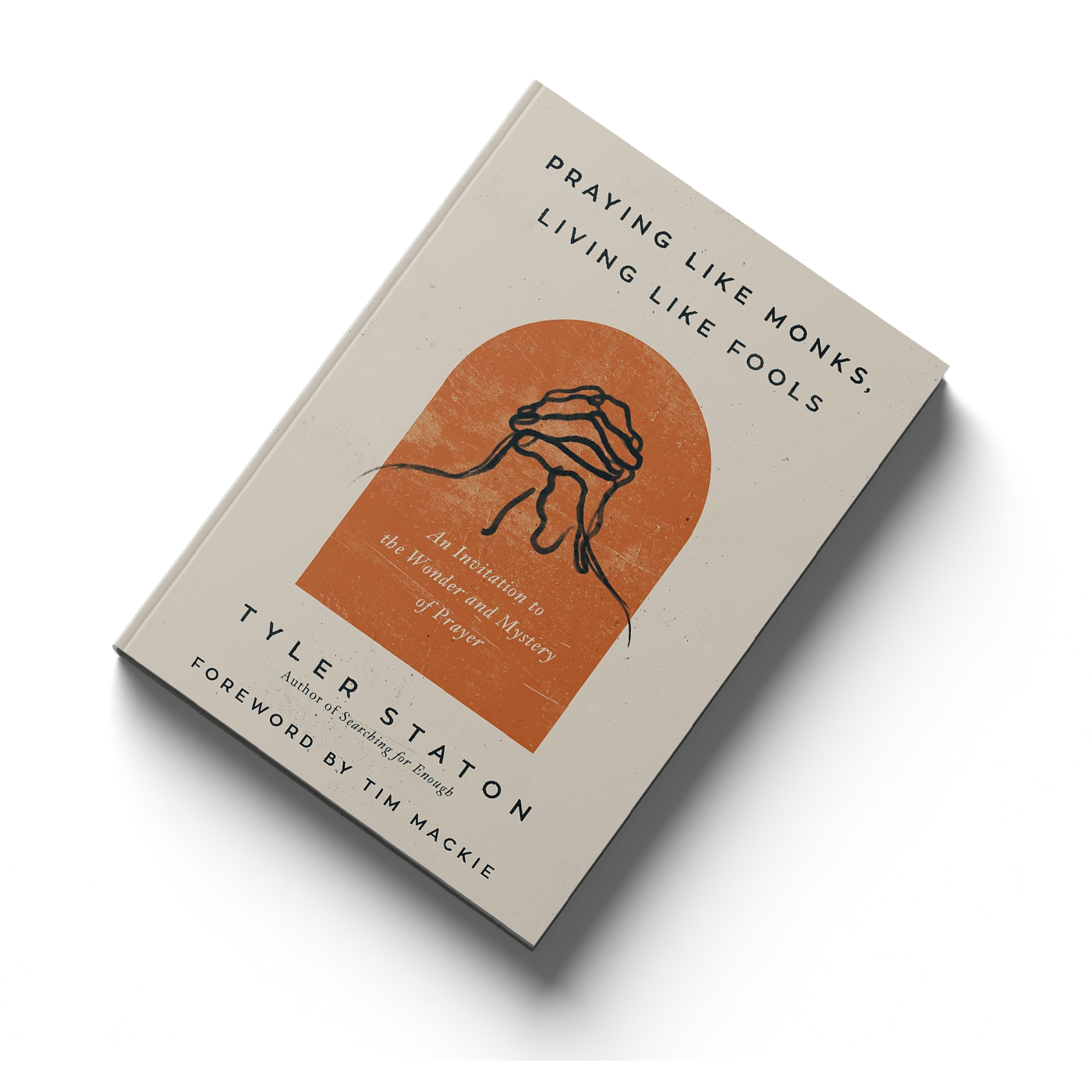 Book titled 'Praying Like Monks, Living Like Fools' by T. M. St. John, with a cover illustration of a hand in prayer, against an orange background.