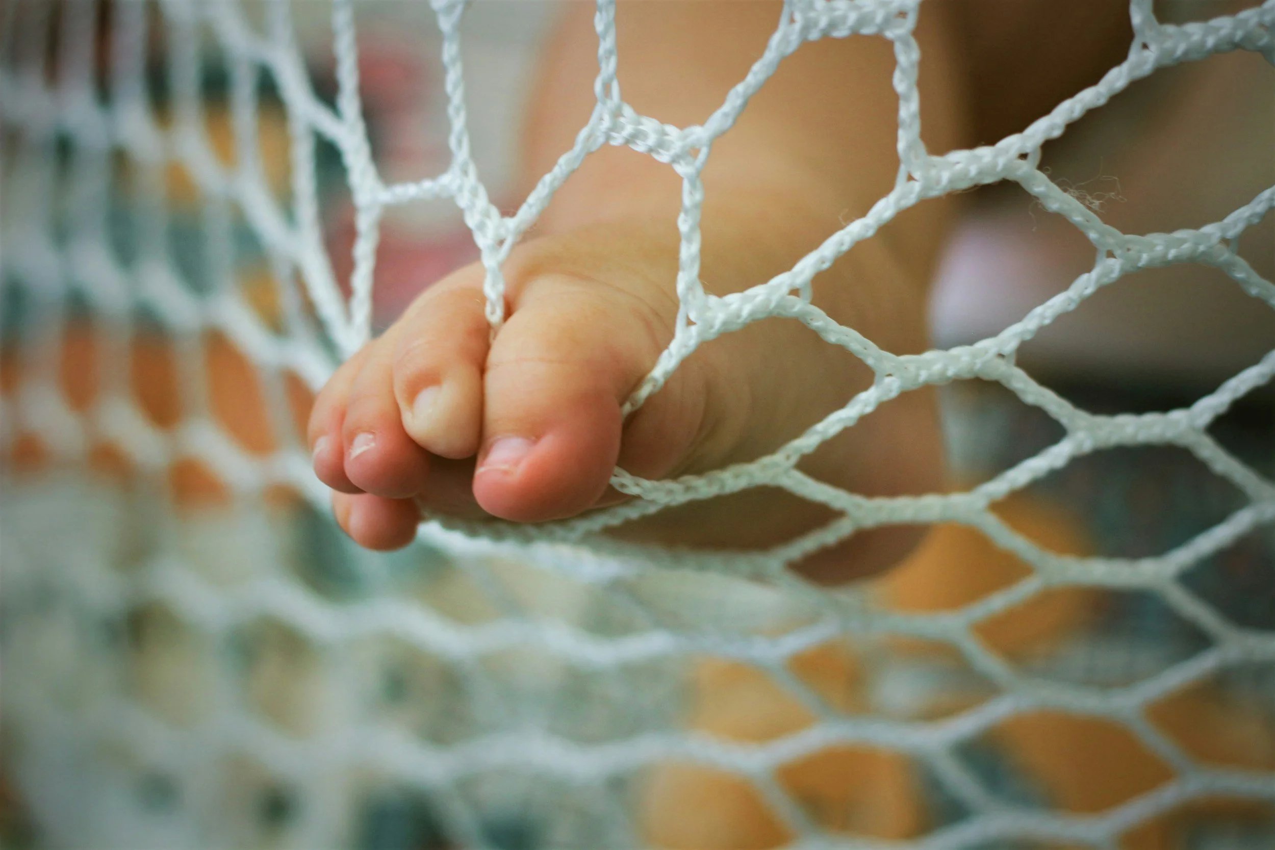 Hand, die in ein Volleyballnetz greift.
