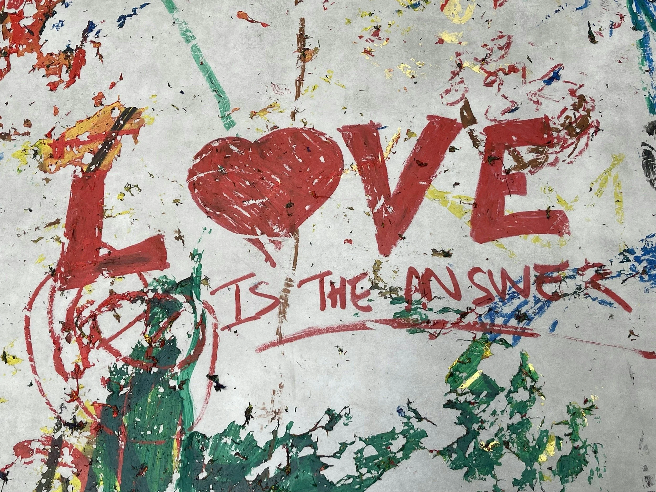 Ein farbenfrohes Gemälde mit dem Wort "LOVE" in großen roten Buchstaben, umgeben von bunten Farbklecksen und Scherenschnitten, die ein Herz bilden.