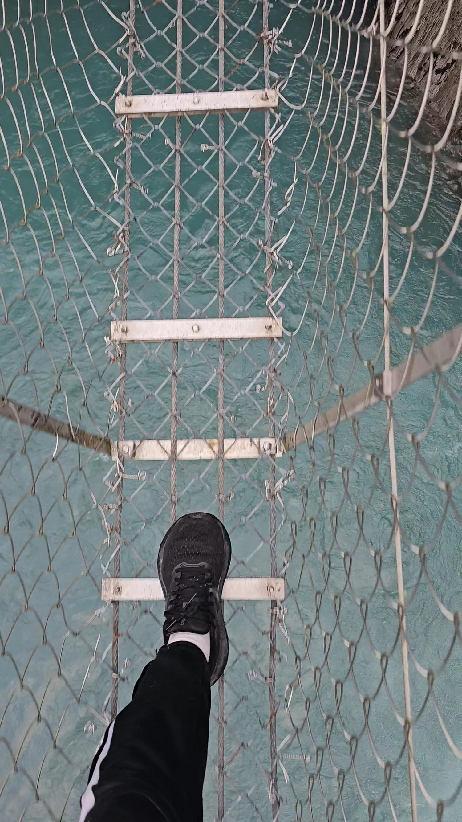 Looking straight down through the open wire walkway of the Cesspool Swing Bridge