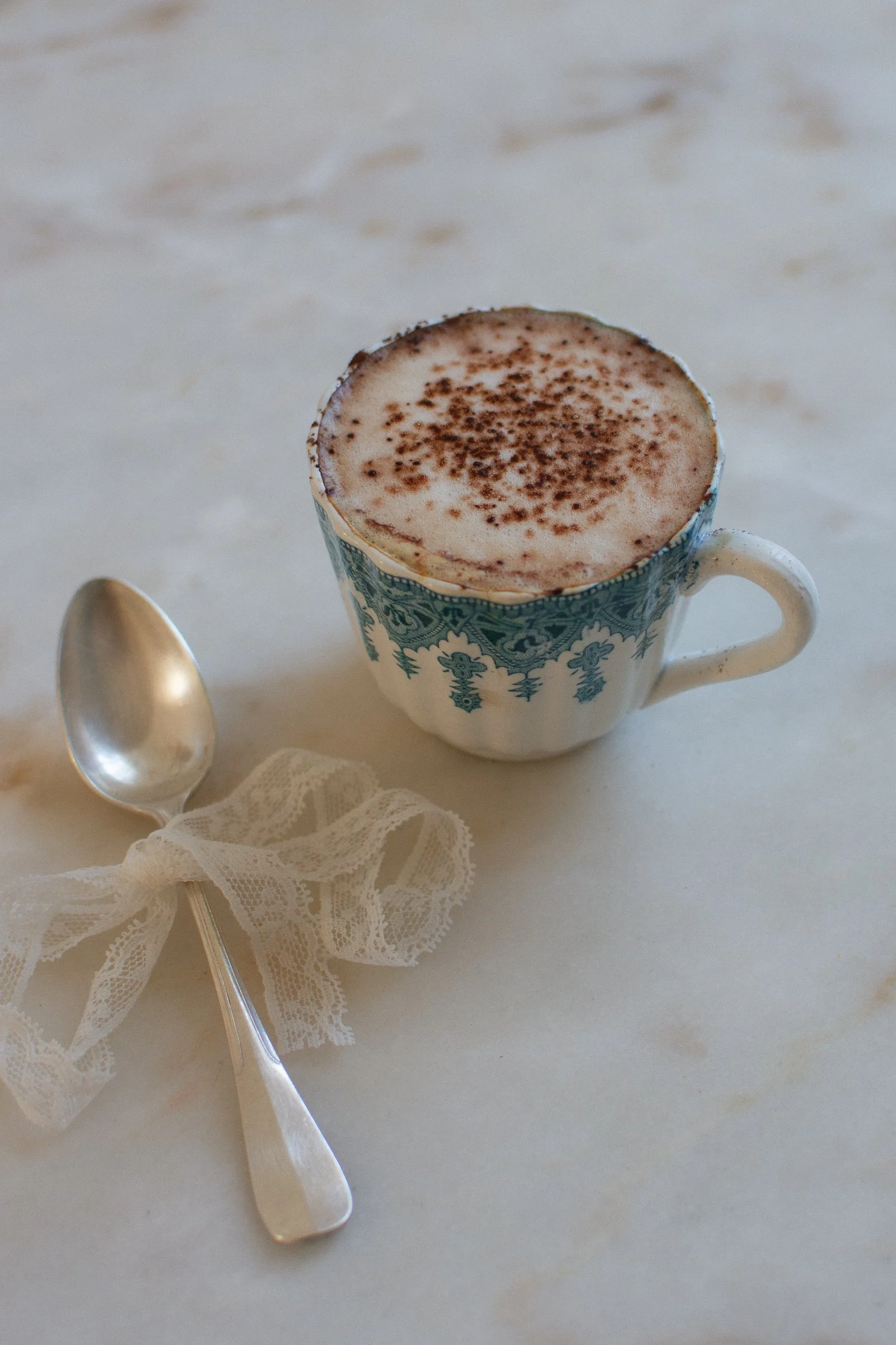 Tasse ancienne terre de fer et petite cuillère en métal argenté sur une table en lin