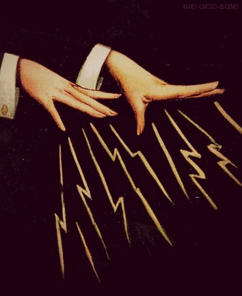 Two hands with long fingers arranged over a black surface with yellow lightning bolt patterns.