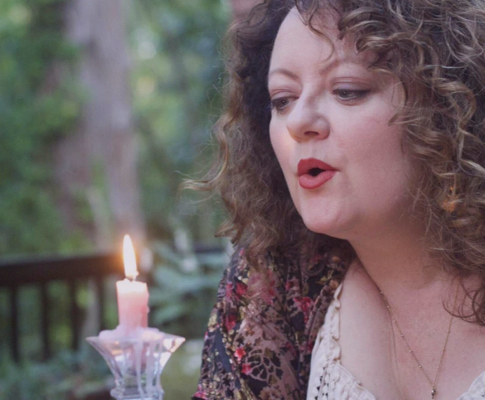 Sarah Blue Cloud beside a lit candle in an outdoor ceremony.