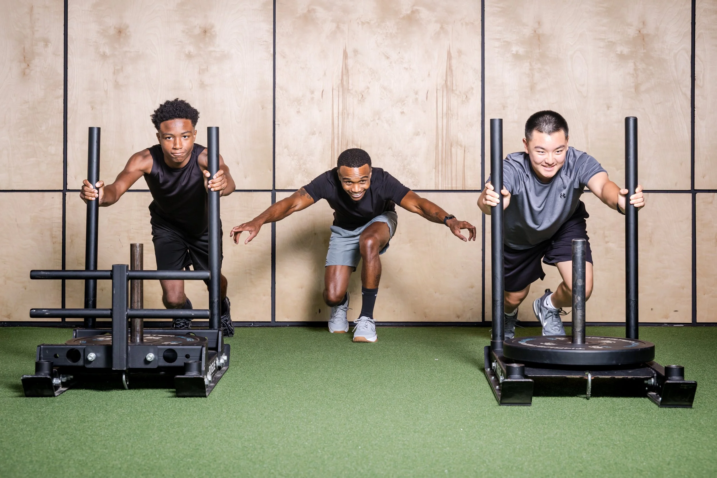 Chris Taylor coaching two youth athletes during partner sled training.