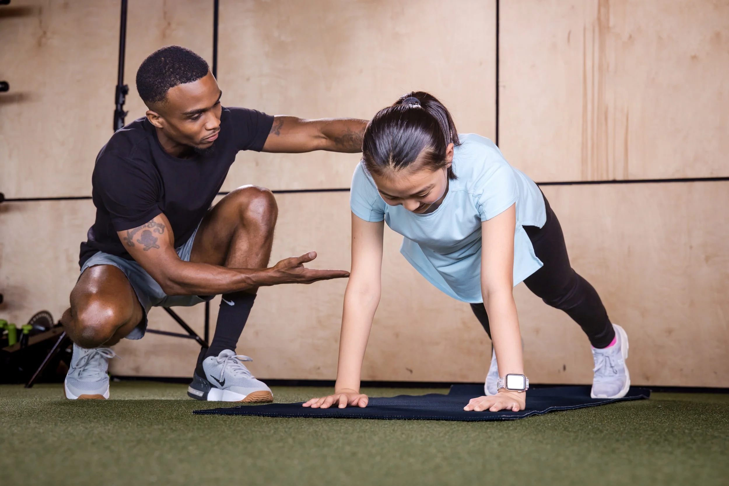 Chris Taylor coaching a youth athlete through a push up.