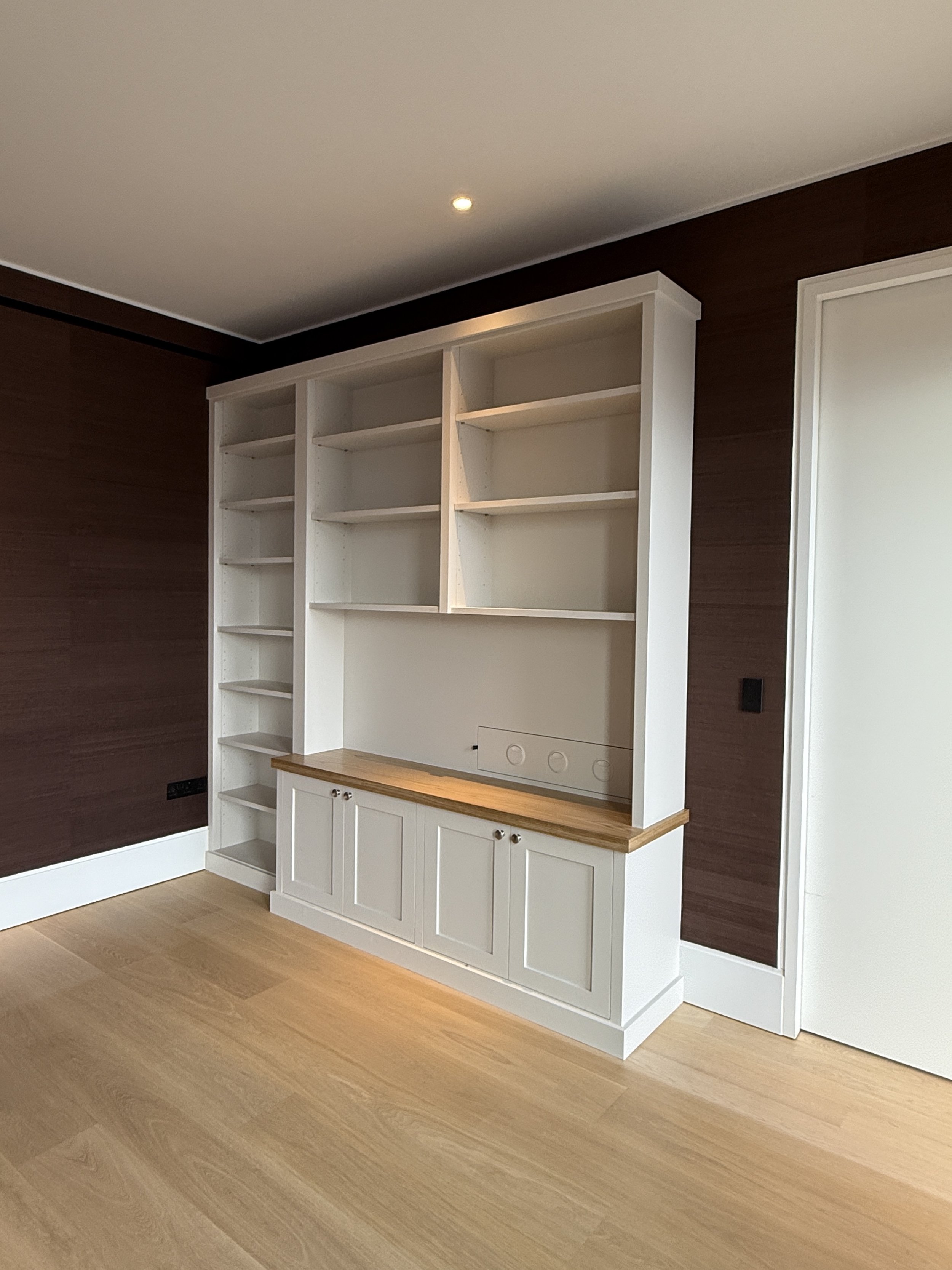 Professional interior paint job showing freshly painted white cabinetry and matching white baseboards contrasting with dark fabric lined walls.