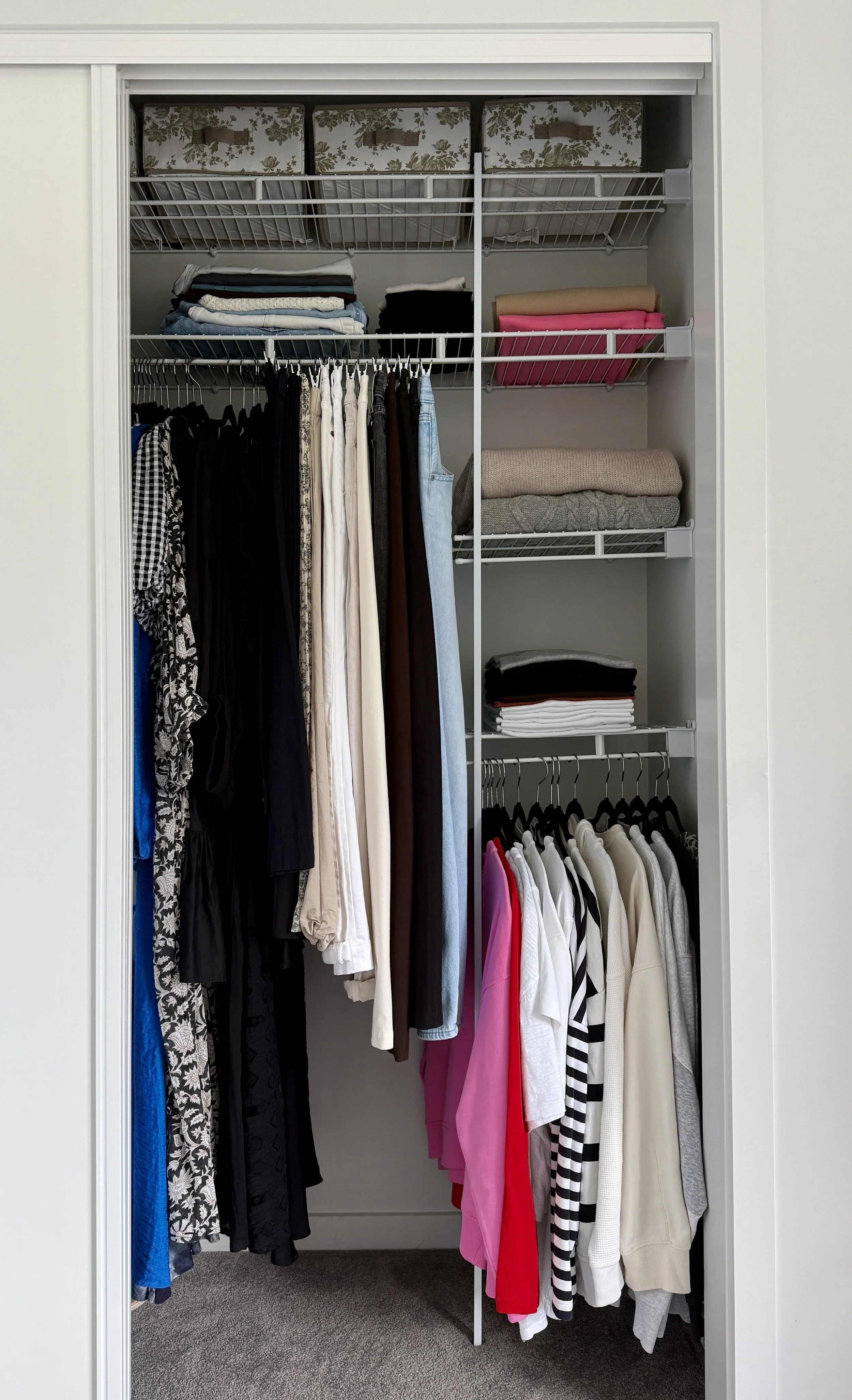 Decluttered bedroom closet storage system utilizing upper wire shelves, fabric bins, and dual hanging rods to maximize space.