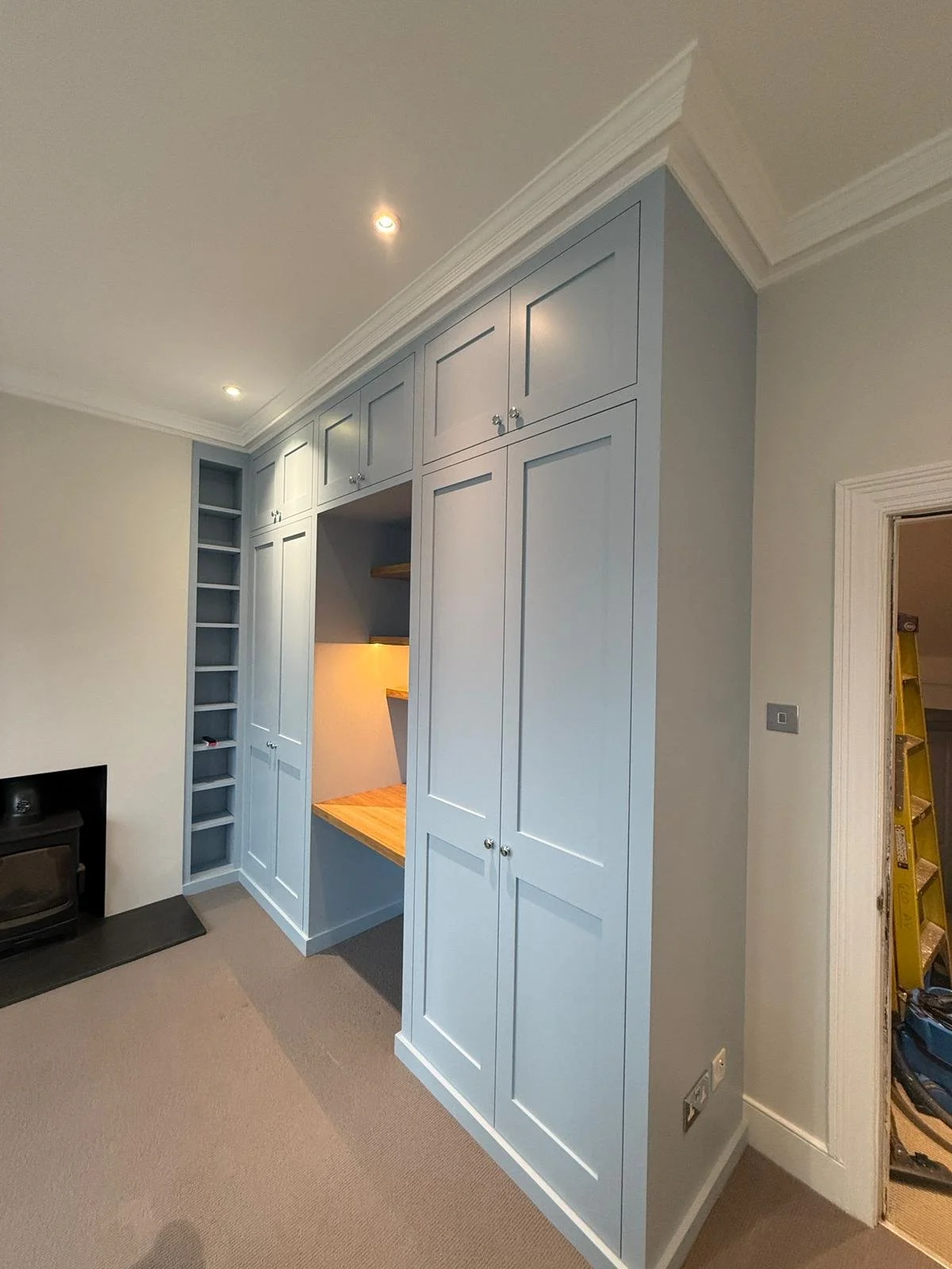 Flawlessly painted light blue shaker cabinets contrasted against crisp white crown molding and trim work in a renovated room.