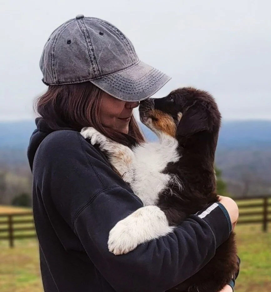 Main Street K9 owner holding a puppy as the puppy touches noses with her