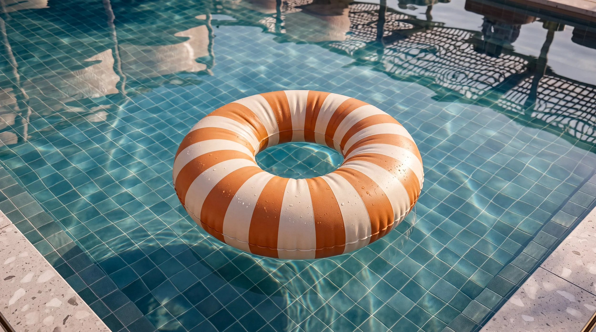 Orange and white striped life preserver floating in a swimming pool with blue tile lining.