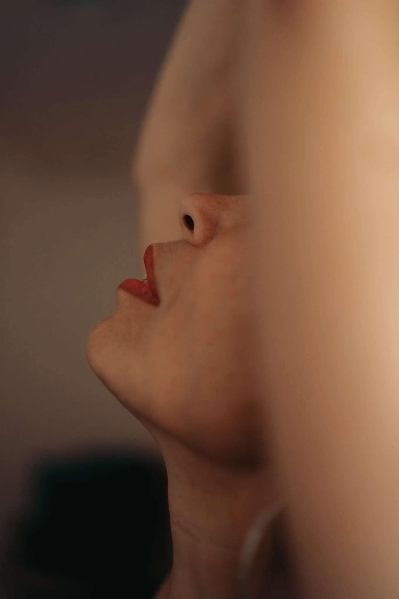 Close-up profile of a person's face with focus on their nose, lips, and part of the cheek, with blurred background.