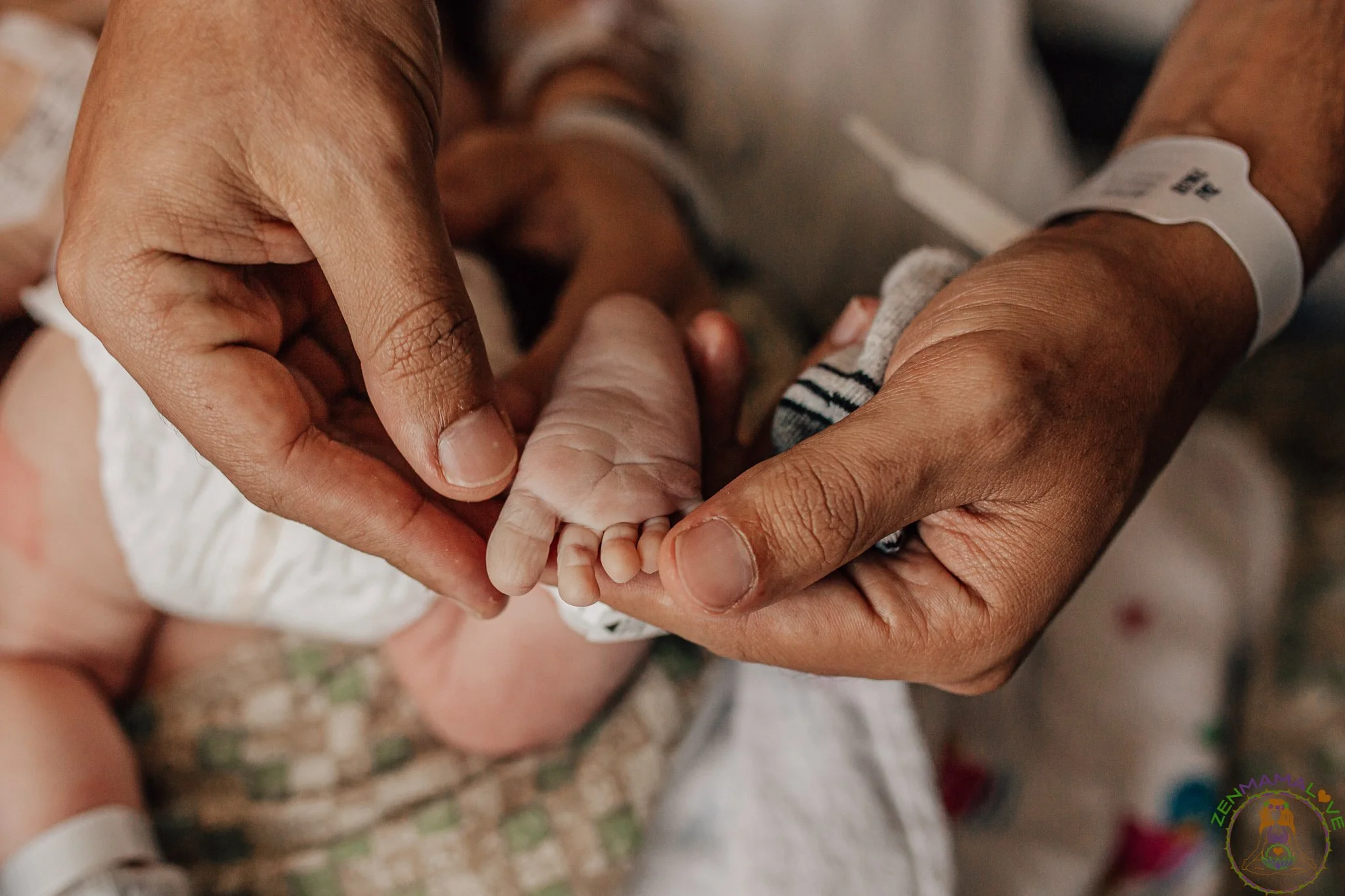 Close-up of a person holding a baby's hand, with a hospital wristband visible on their wrist.