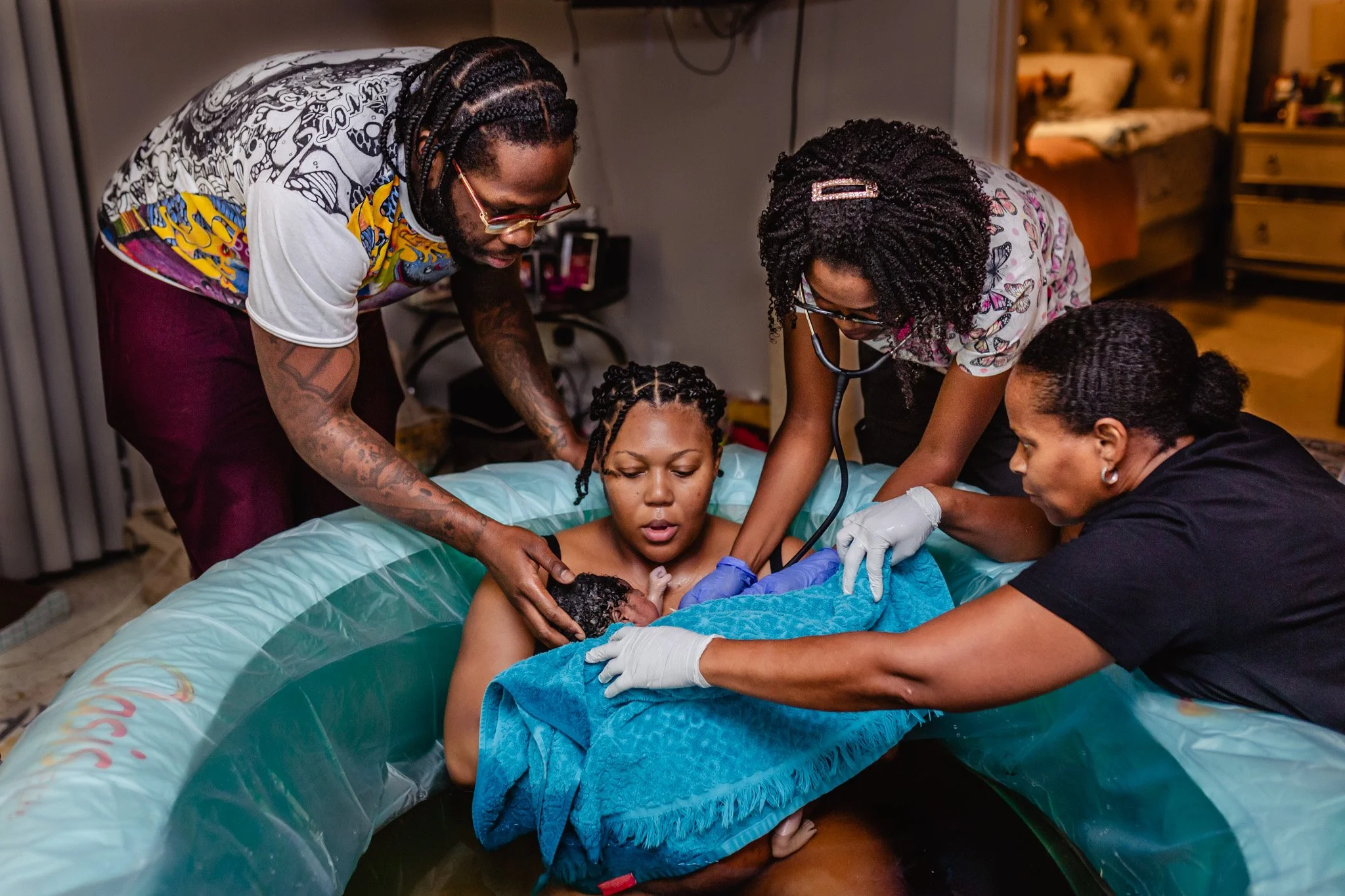 A group of healthcare professionals delivering a baby in a home setting.