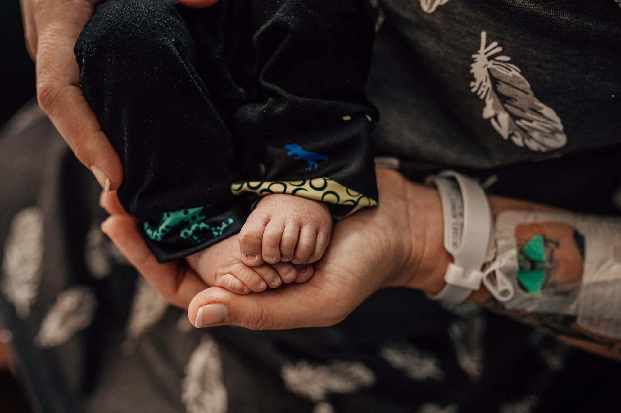 A healthcare worker holding a newborn baby's tiny hand.