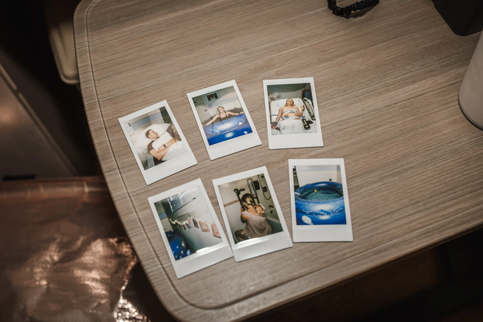 Multiple instant film photographs laid out on a wooden surface, including images of people, objects, and scenes.