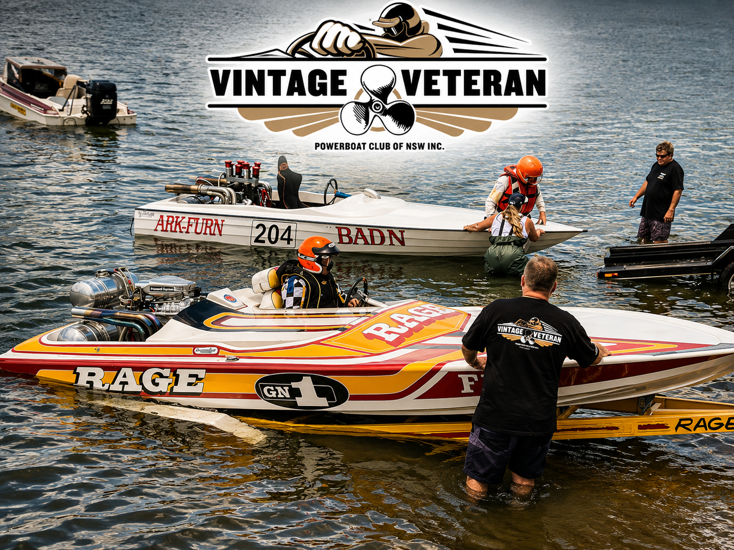Several vintage racing powerboats with outboard engines and racing decals are on the water, with crew members and officials preparing for a race at a vintage veteran powerboat club event.
