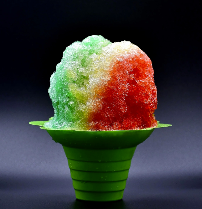 Colored shaved ice in a green cup with red, white, and green syrup