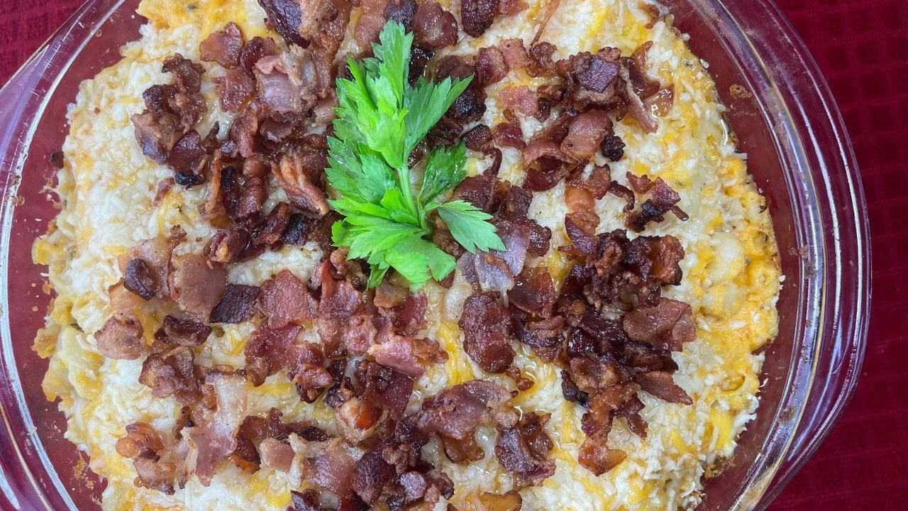 Baked mac and cheese dish topped with cooked bacon pieces and garnished with a sprig of parsley.
