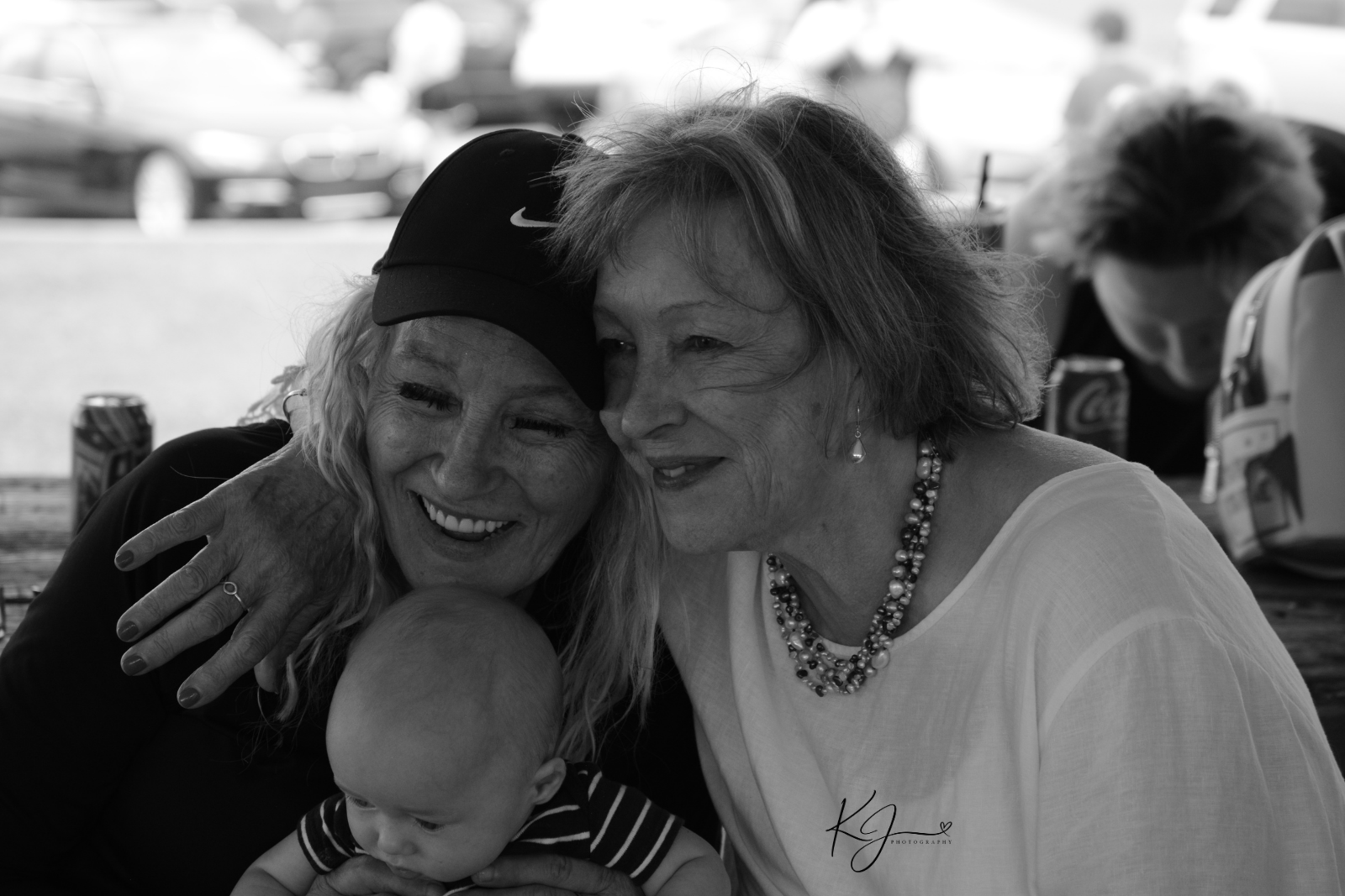 Three women and a baby hugging and smiling, black and white photograph.