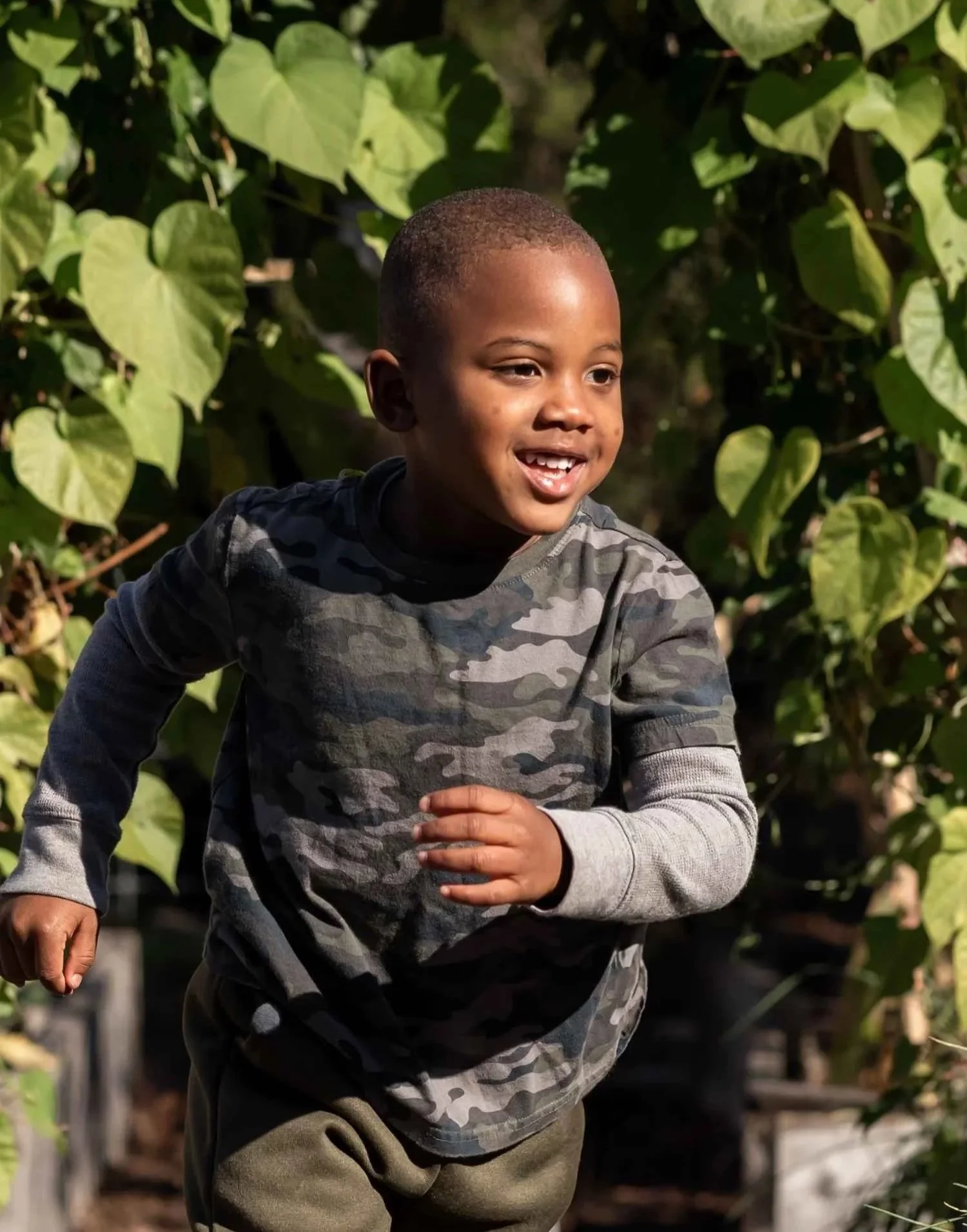 A Nantucket Lighthouse School Small School student runs joyfully through lush greenery in the school garden during horticulture class, exploring nature and enjoying outdoor learning.