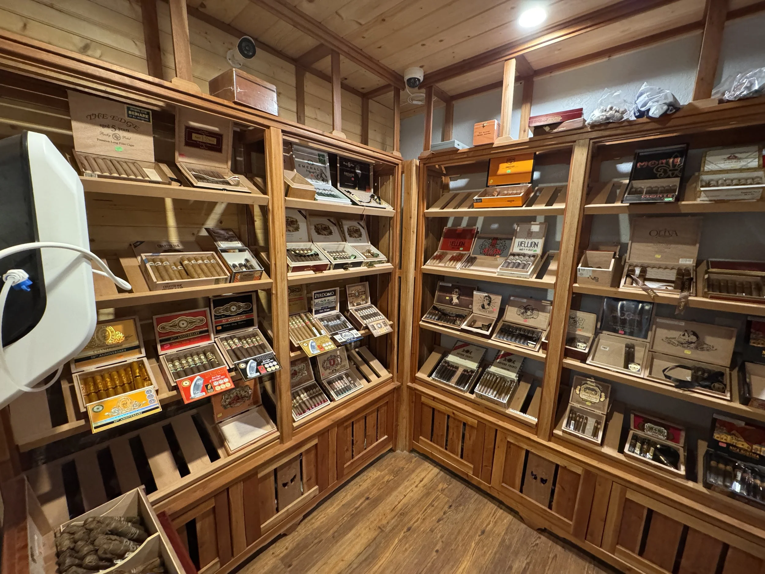 Wooden shelves displaying assorted cigars and cigar boxes in a cigar shop.
