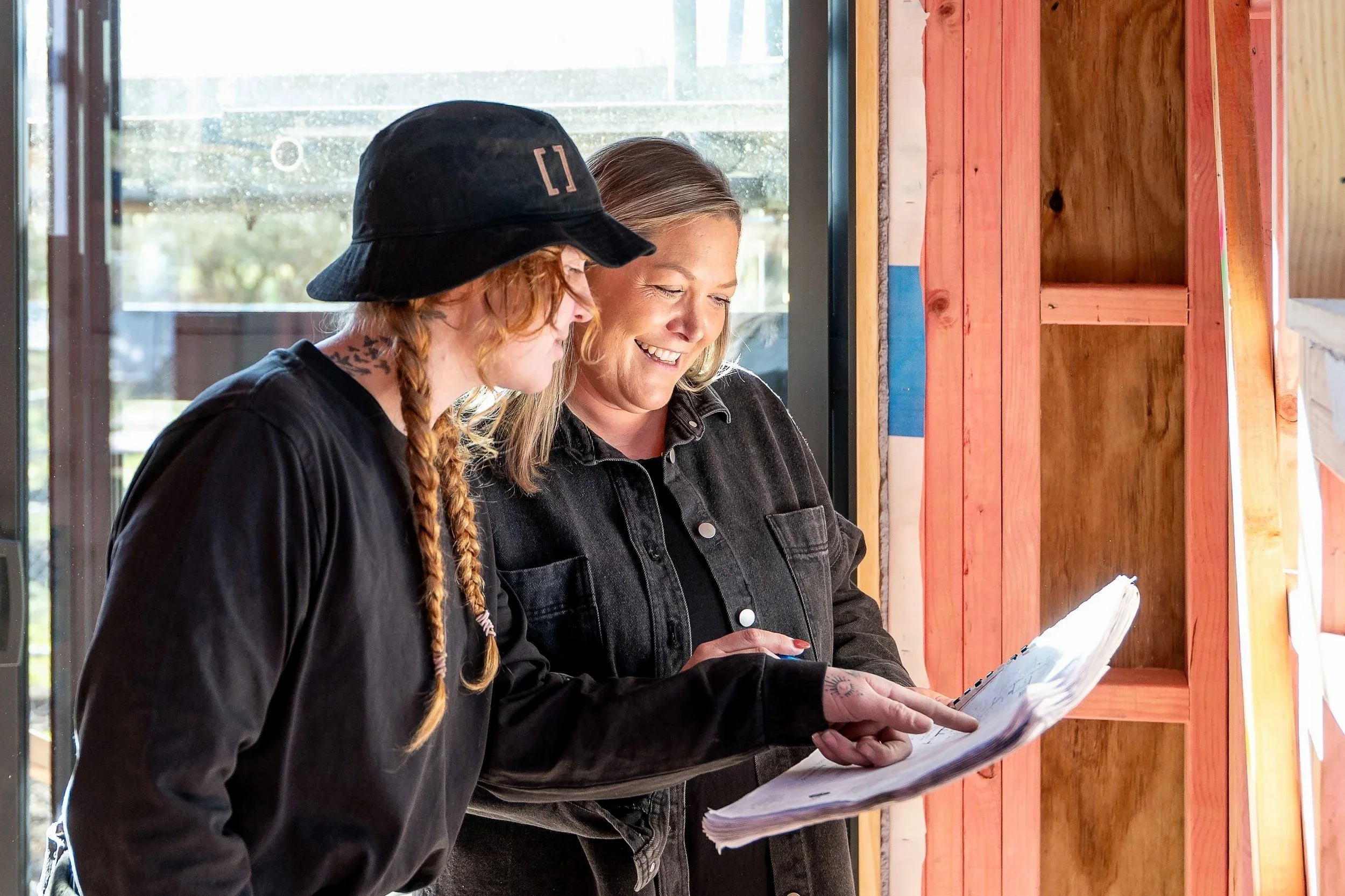 Two women looking at a document or blueprint together inside a building under construction. Renovations, Extensions & Additional Dwellings Canterbury | Alterhouse