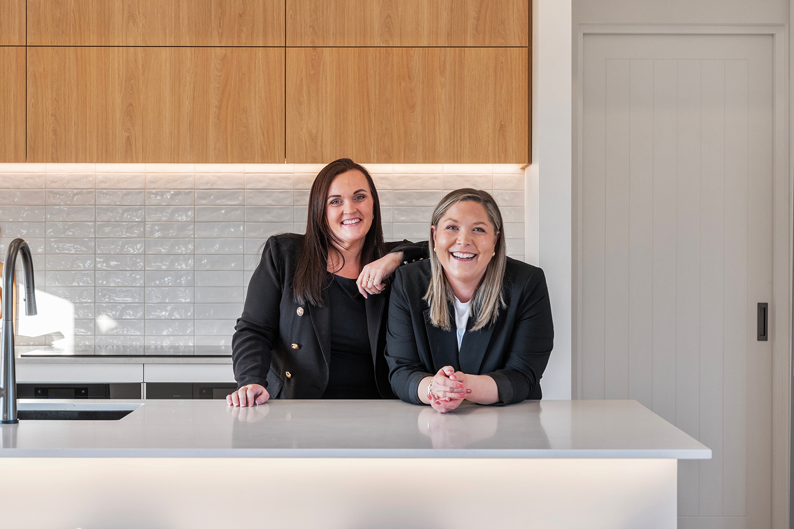 Two smiling women in black blazers leaning on a white kitchen counter. Renovations, Extensions & Additional Dwellings Canterbury | Alterhouse