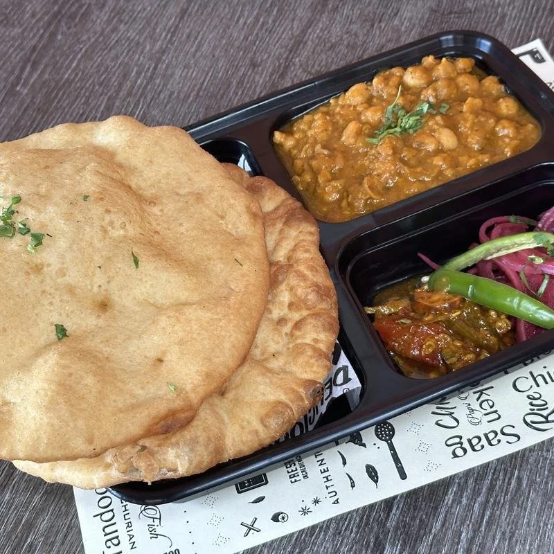 Indian meal with naan bread, two curry dishes, and pickled vegetables.